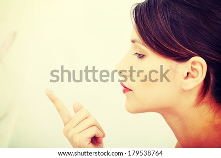 Beautiful young caucasian woman putting a contact lens at bathroom