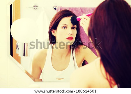 Mirror reflection of a beautiful young woman doing the morning make-up.
