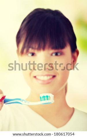 Young beautiful woman washing her teeth with blue brush - focus on brush