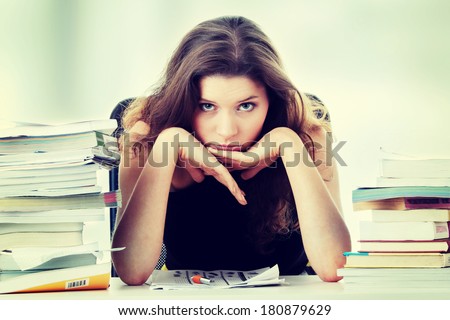 Portrait of young and pretty female student with books around