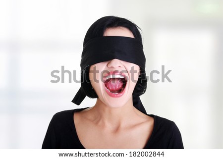 Portrait of a beautiful frighten young blindfold woman screaming