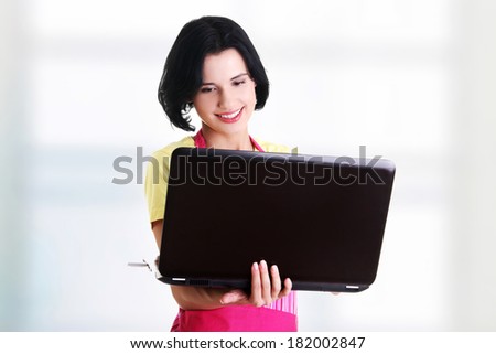 Modern housewife or female worker with laptop wearing pink apron