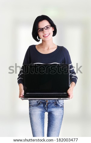 Young woman holding and showing screen of 17 inch laptop