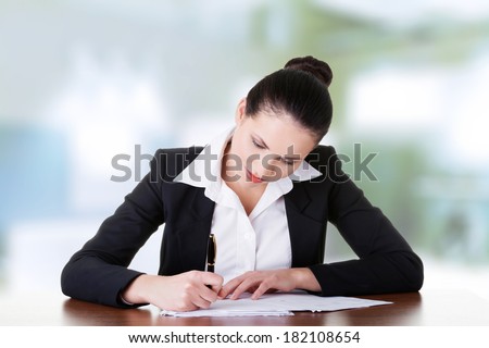 Beautiful attractive corporate lawyer business woman sitting at desk and writing blank paper page