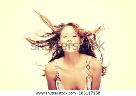 Young beautiful woman in elegant, evening, white dress dancing with wind (hair blowing), isolated on white background.