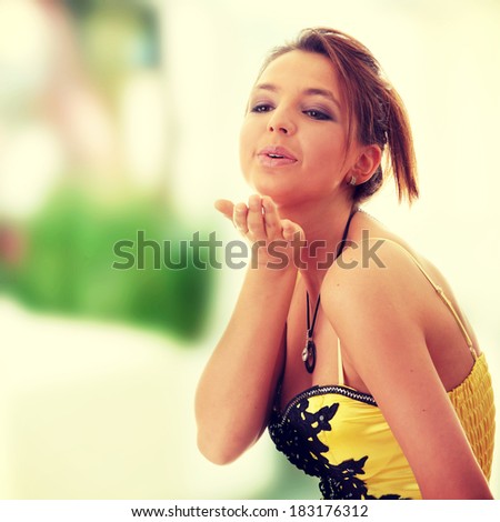 Sweet young woman (teenage girl) in yellow/black dress sending a kiss