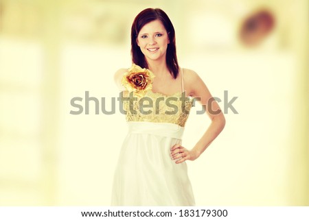 Young beautiful woman in elegant, evening, gold dress, holding gold rose isolated on white background.