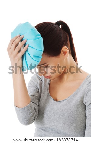 Young beautiful woman is haveng a headache and holding ice bag. Isolated on white.