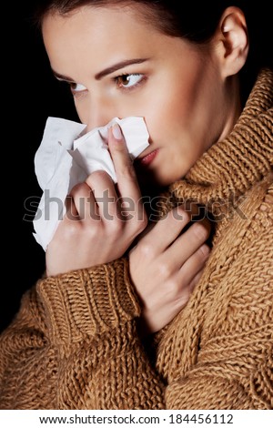 Young woman having depression with tissue. On black background.