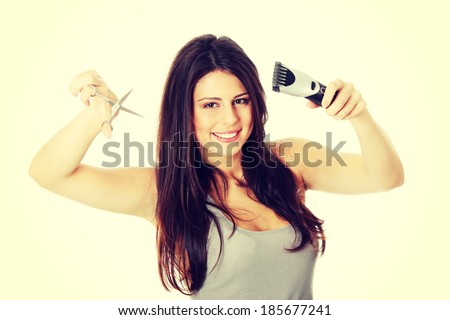 Young beautiful female hairdresser holding scissors and hair clipper