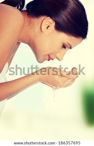 Young beautiful happy female washing her face with clear water