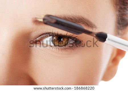 Beautiful woman brushing her eyebrow. Close up.