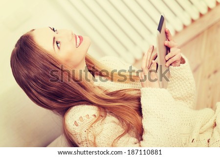 Beautiful caucasian woman sitting on the wooden floor with tablet.