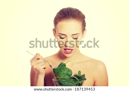 Beautiful caucasian topless woman eating lettuce from a bowl with fork. Isolated on white.