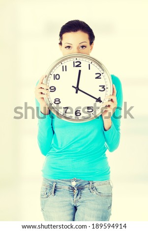 Shocked woman holding office clock