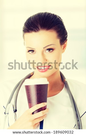 Tired female doctor with coffee. Coffee addiction concept.