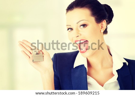Portrait of a happy attractive caucasian businesswoman, real estate agent, holding a house key against a white background