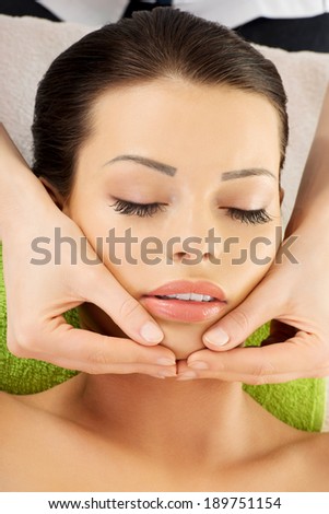 Beautiful young relaxed woman enjoy receiving face massage therapy at spa saloon