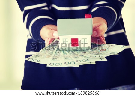 Woman holding PLN ( polish zloty ) bills and house model  - real estate loan concept