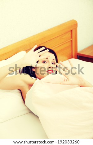 Closeup of a terrified woman defensing with her hands in bed.