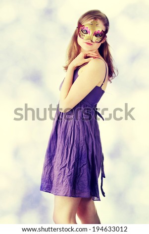 Young beautiful woman in violet dress wearing carnival mask