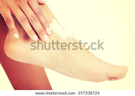 Female hands treating feet with moisturizing cream.