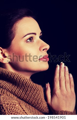 Young woman praying. Over black background.