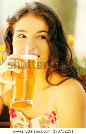 Attractive young woman drinking beer on sidewalk cafe.