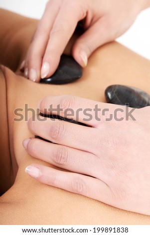 Beautiful woman lying on spa salon having stone massage. Spa concept.