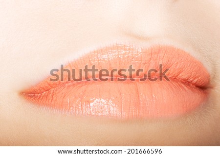Woman\'s peachy lips. Closeup. Skin colour background.