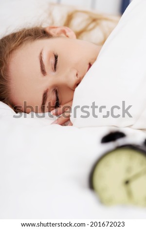 Beautiful sleeping woman with alarm clock. Focus on woman.