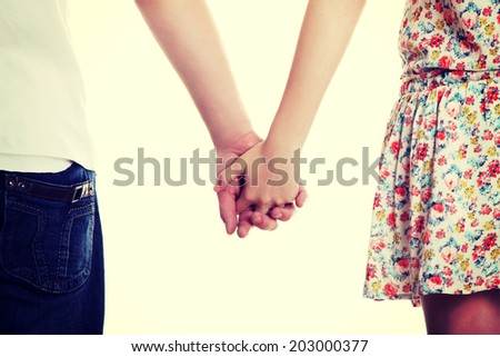 Young couple are standing a back side and holding hands.