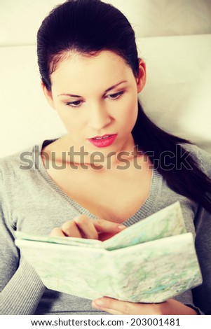 Young woman is searching something in map.