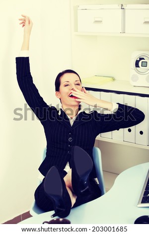 A photo of business woman with legs on desk during break.