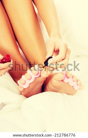 Attractive woman painting her toes in bed.