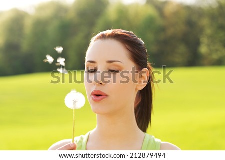 Woman blowing on a dandelion.