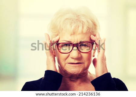 An old woman is eye glasses is having a headache. Isolated on white.