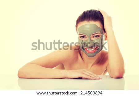 Beautifu toplessl woman with facial mask with hands on table. Isolated on white.