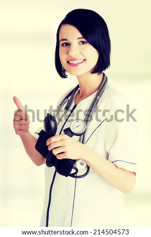 Woman doctor with blood pressure gauge gesturing thumbs up