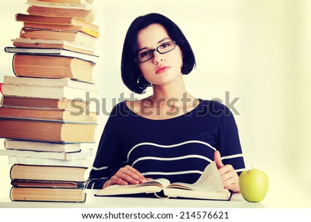 Young student woman with books studying at the desk, isolated on white background