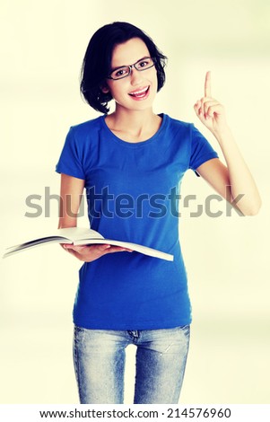 Studying happy young woman reading her notebook for school and pointing on copy space.