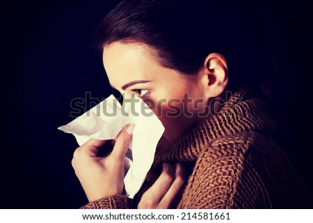 Sad young girl with tissue. Over black background.