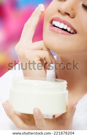 Beautiful woman applies face cream.