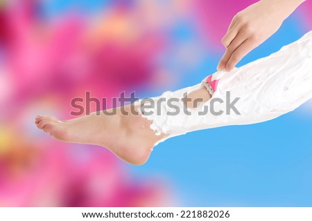 Beautiful woman is shaving her legs with razor and foam