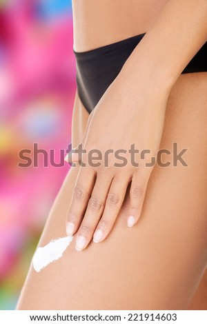Female smooth legs with one hand lotioning. Closeup