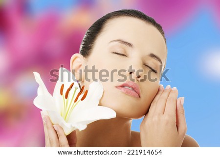 Portrait of beautiful young woman with health skin and with lily flower