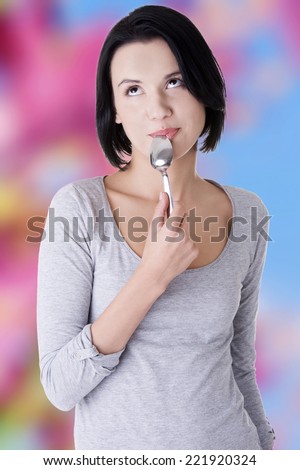 Portrait of young smiling woman with spoon in her mouth -pleasure from eating