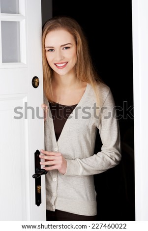 Young woman opening her house door