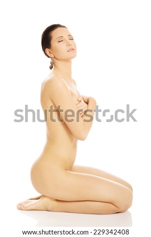 Side view of attractive naked woman sitting on knees.