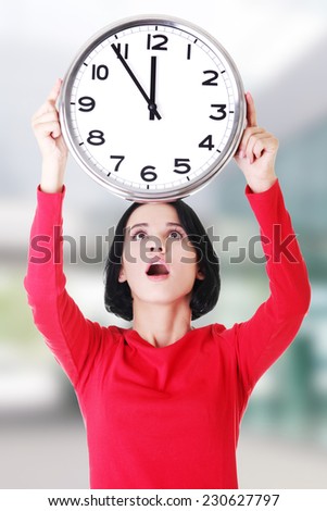 Shocked woman holding office clock.